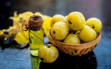 Amla berries on table with oil jar